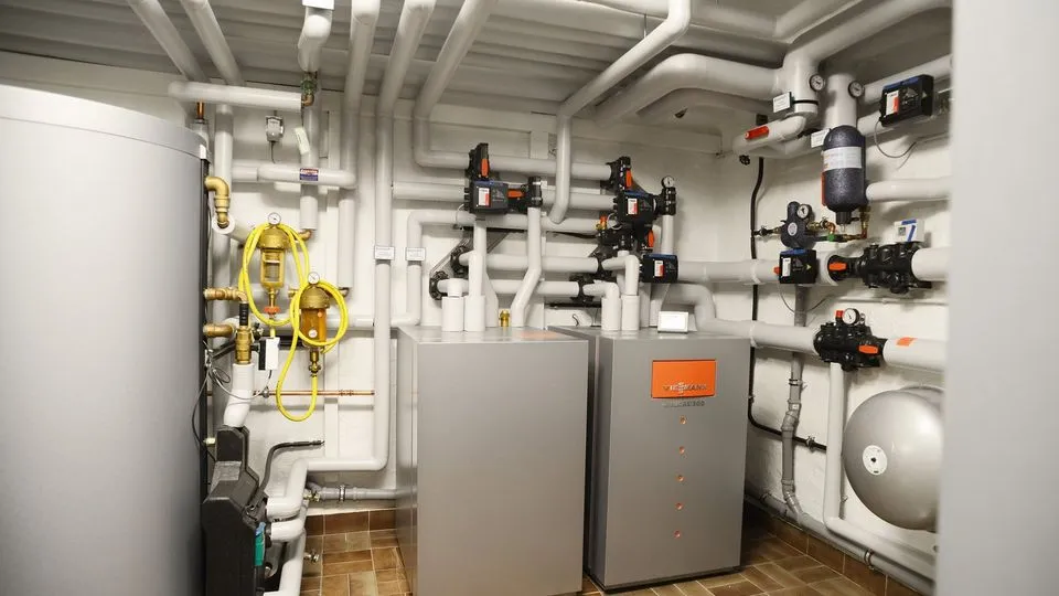 Ein Wärmepumpe und mehrere Rohre, die von der Wärmepumpe wegführen und an der Decke des Raums verlaufen. 